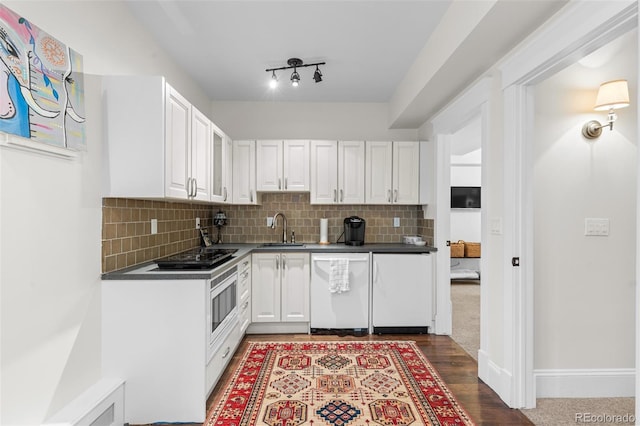 kitchen with black cooktop, white dishwasher, a sink, and white cabinetry