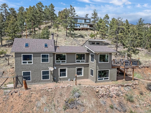 back of property featuring stairs, a shingled roof, and a deck