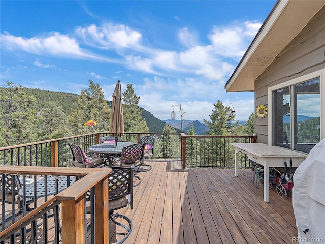 wooden deck with outdoor dining space and a mountain view