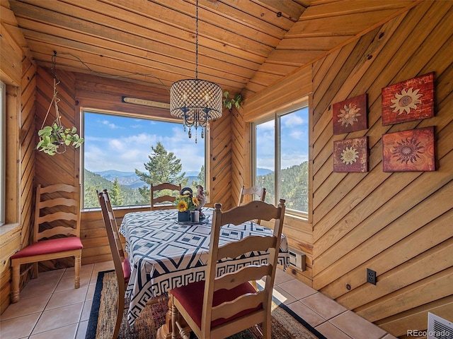 tiled dining area featuring wood walls, lofted ceiling, an inviting chandelier, a mountain view, and visible vents