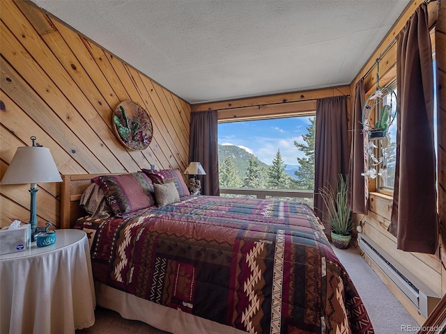 bedroom featuring carpet flooring, wooden walls, and a baseboard heating unit