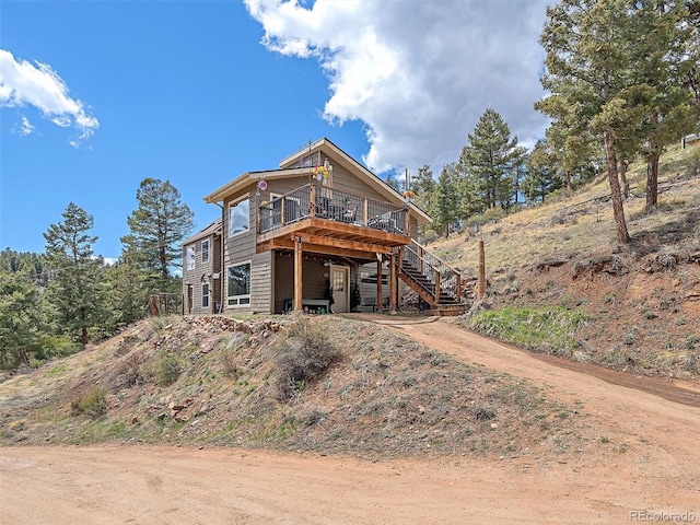 rear view of house featuring driveway, a deck, and stairs