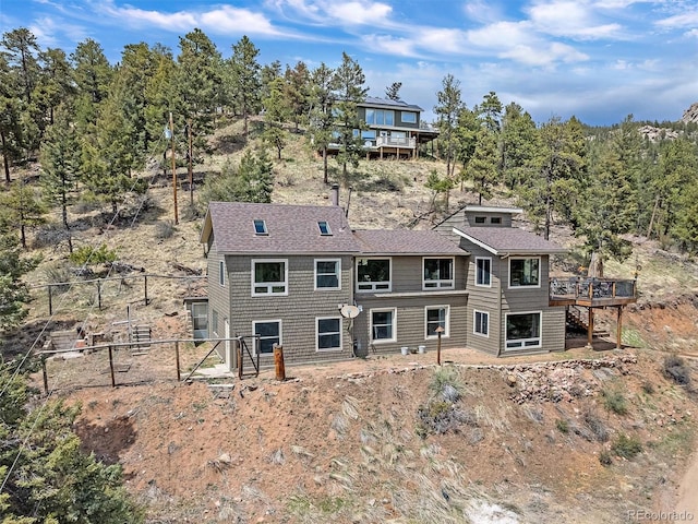 back of property featuring fence, roof with shingles, and a deck