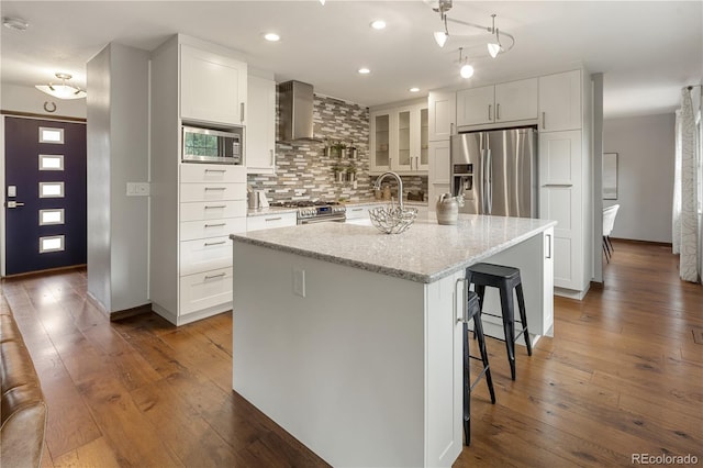 5292 W Fair Dr, Littleton, CO 80123 - kitchen featuring stainless steel appliances, wall chimney exhaust hood, decorative backsplash, white cabinetry, and recessed lighting