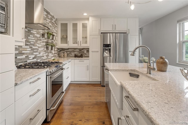 5292 W Fair Dr, Littleton, CO 80123 - kitchen with stainless steel appliances, wall chimney range hood, wood finished floors, decorative backsplash, and recessed lighting