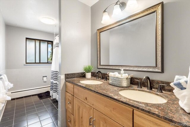 591 Nome St, Aurora, CO 80010 - bathroom with baseboard heating, tile patterned floors, tile walls, double vanity, and a wainscoted wall