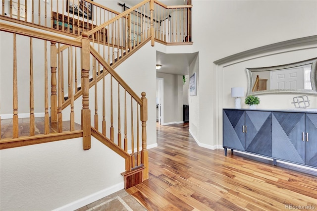 stairs with a towering ceiling and wood-type flooring