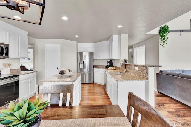 kitchen with stainless steel appliances, white cabinetry, sink, and kitchen peninsula