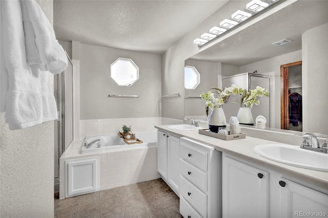 bathroom with vanity, a textured ceiling, and separate shower and tub