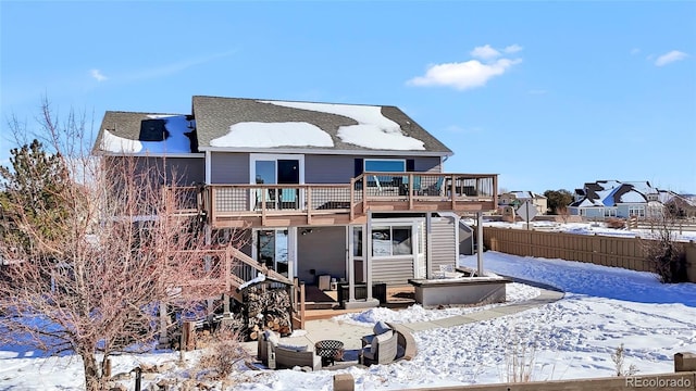 snow covered back of property with a deck