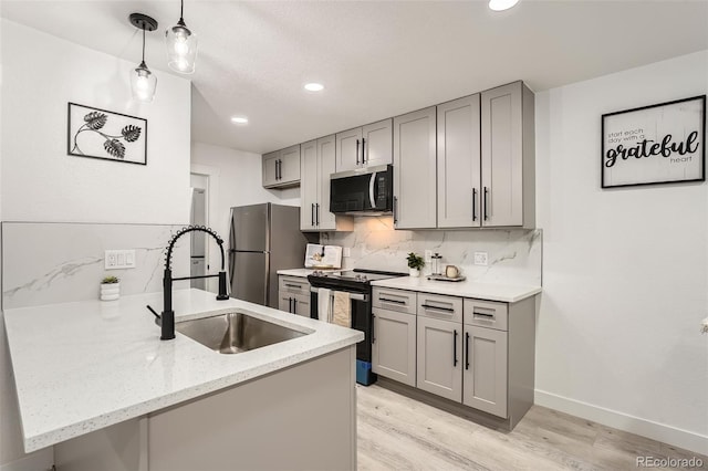 kitchen featuring backsplash, sink, appliances with stainless steel finishes, decorative light fixtures, and kitchen peninsula