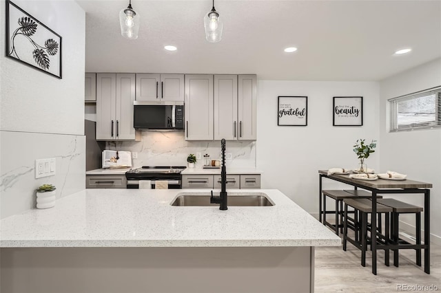 kitchen with stainless steel electric stove, decorative backsplash, gray cabinetry, and sink