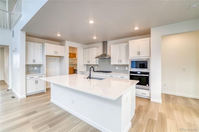 8595 Silverton Ln, Littleton, CO 80125 - kitchen with a center island with sink, stainless steel appliances, wall chimney range hood, and white cabinetry