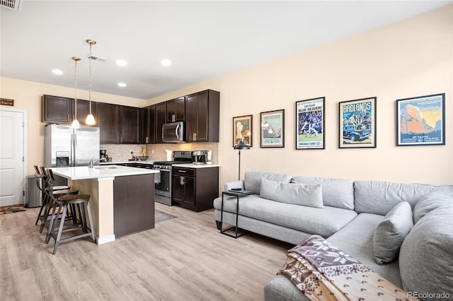 15546 W 64th Loop Unit C, Arvada, CO 80007 - kitchen with stainless steel appliances, open floor plan, a breakfast bar area, light wood finished floors, and recessed lighting
