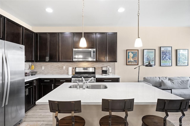 15546 W 64th Loop Unit C, Arvada, CO 80007 - kitchen with stainless steel appliances, a breakfast bar area, light wood finished floors, open floor plan, and backsplash