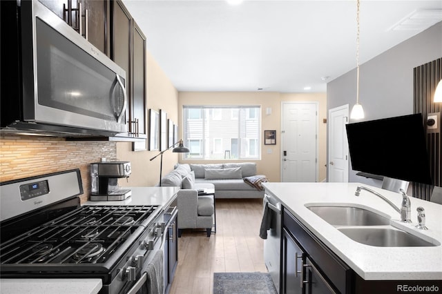 15546 W 64th Loop Unit C, Arvada, CO 80007 - kitchen with stainless steel appliances, open floor plan, decorative backsplash, light wood-type flooring, and hanging light fixtures