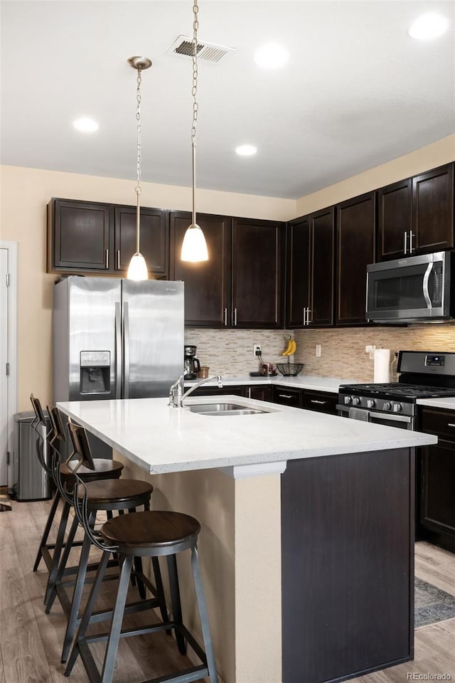 15546 W 64th Loop Unit C, Arvada, CO 80007 - kitchen with stainless steel appliances, light wood-style flooring, a kitchen island with sink, tasteful backsplash, and recessed lighting