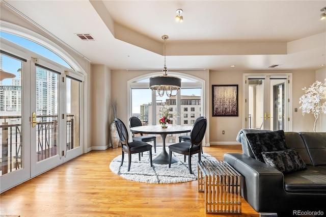 dining space with french doors, a chandelier, a tray ceiling, baseboards, and recessed lighting