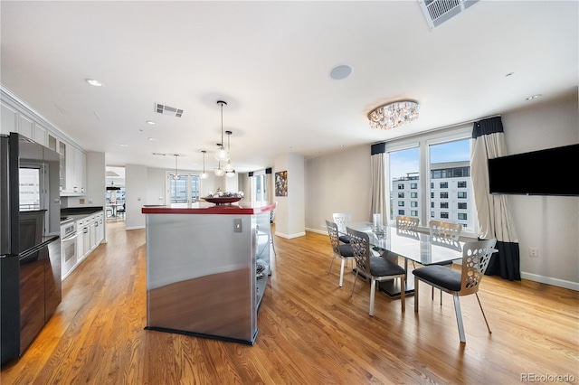 kitchen featuring light wood-type flooring, white cabinetry, plenty of natural light, and freestanding refrigerator