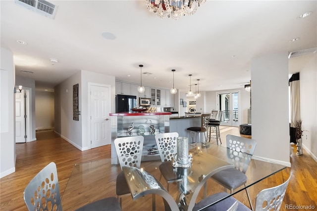 dining area featuring baseboards, light wood finished floors, and a chandelier