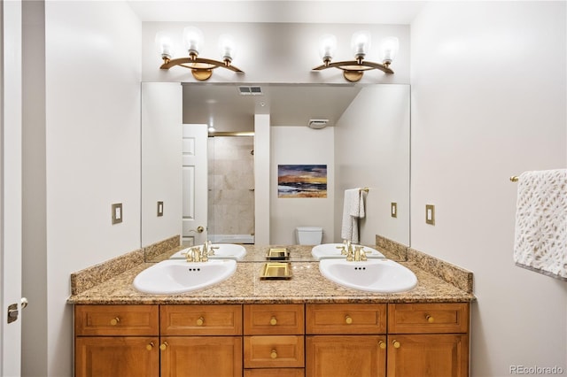 bathroom featuring a tile shower, toilet, and double vanity