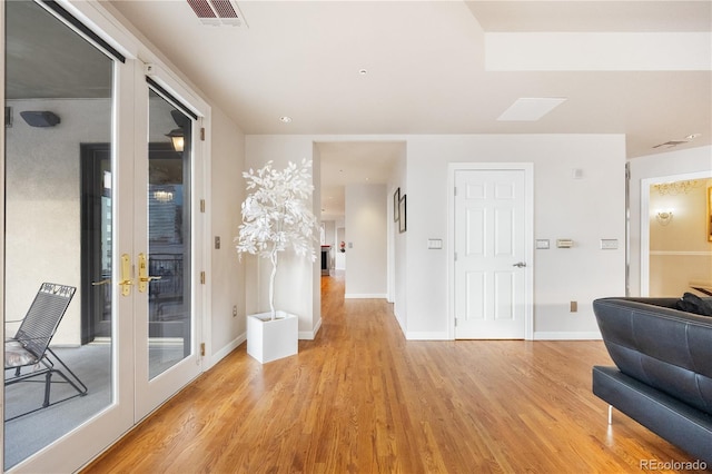 corridor featuring light wood finished floors and baseboards