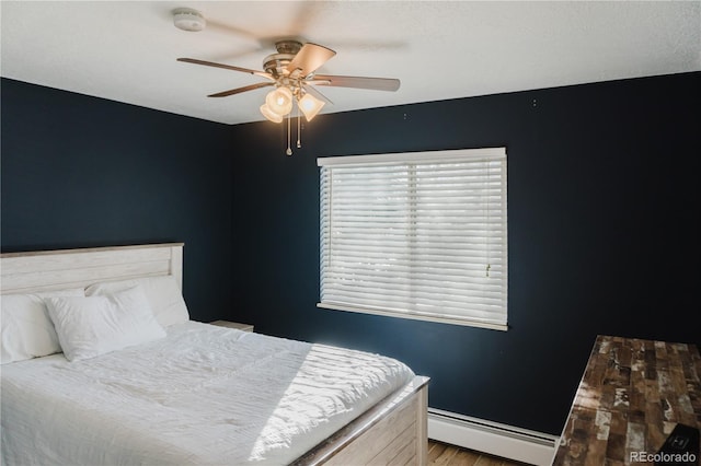 bedroom featuring hardwood / wood-style floors, ceiling fan, and a baseboard heating unit