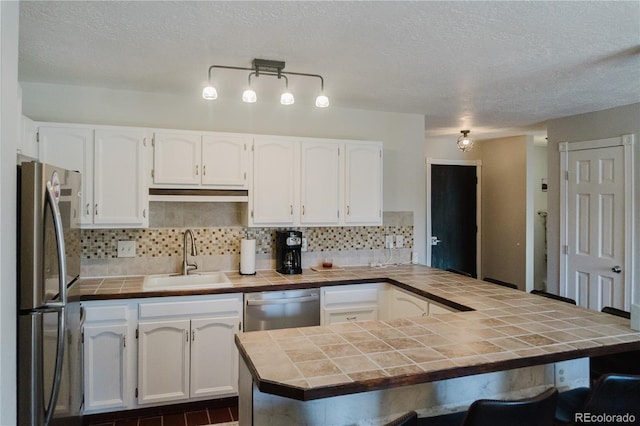 kitchen featuring tile countertops, white cabinets, sink, and stainless steel appliances