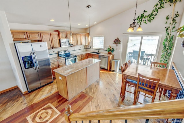 kitchen featuring stainless steel appliances, sink, hanging light fixtures, a kitchen island, and vaulted ceiling