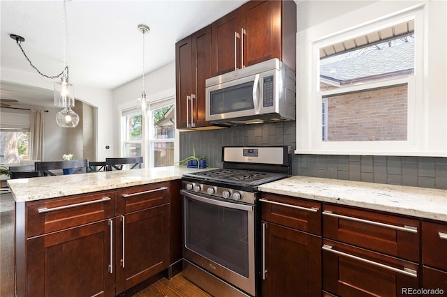 kitchen featuring appliances with stainless steel finishes, a peninsula, backsplash, and light stone countertops