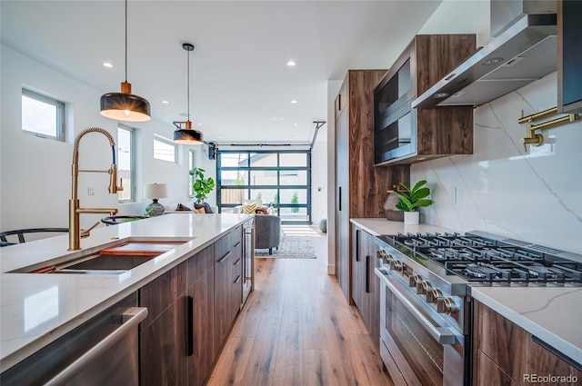 4474 Utica St, Denver, CO 80212 - kitchen featuring modern cabinets, stainless steel appliances, exhaust hood, light wood-style flooring, and light stone counters