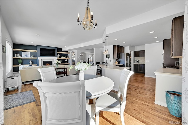 dining area featuring sink, a chandelier, and light wood-type flooring