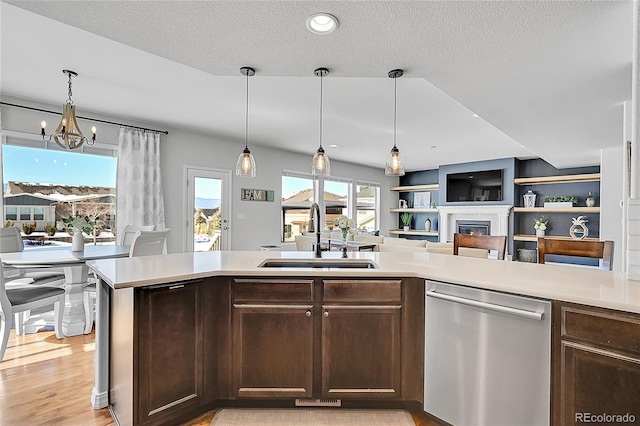 kitchen with sink, hanging light fixtures, dark brown cabinets, light wood-type flooring, and dishwasher