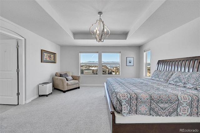 bedroom with a notable chandelier, a raised ceiling, and carpet