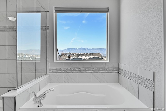 bathroom featuring a mountain view and tiled tub