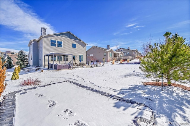 snow covered rear of property with a hot tub