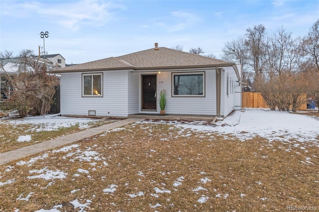 bungalow-style home with roof with shingles and fence