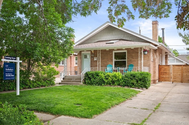 1532 Meade St, Denver, CO 80204 - bungalow-style home featuring covered porch, a chimney, a front yard, brick siding, and concrete driveway