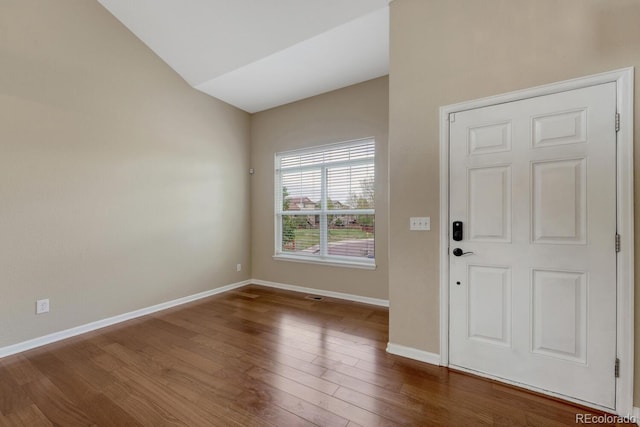 foyer with baseboards, wood finished floors, and vaulted ceiling