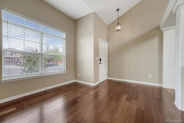 unfurnished room featuring dark wood finished floors, lofted ceiling, and baseboards