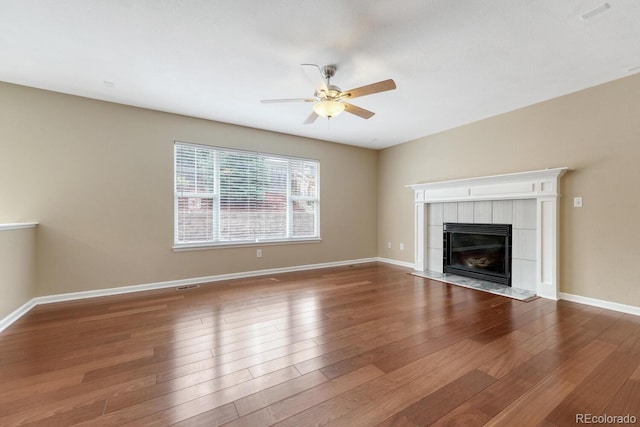 unfurnished living room with ceiling fan, a fireplace, wood finished floors, and baseboards