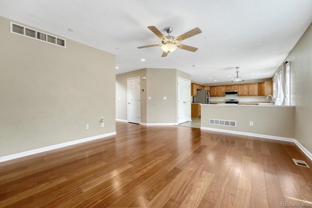unfurnished living room featuring light wood-style flooring, ceiling fan, recessed lighting, baseboards, and a sink