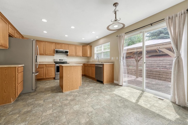 kitchen featuring stainless steel appliances, light countertops, a center island, recessed lighting, and a sink