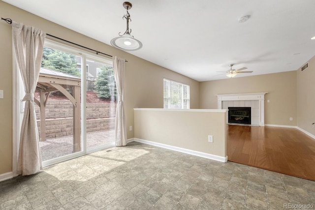 unfurnished living room with a ceiling fan, healthy amount of natural light, baseboards, and a fireplace
