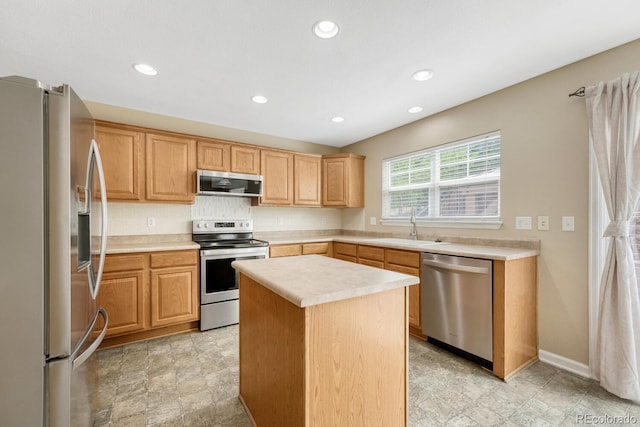 kitchen with stainless steel appliances, light countertops, recessed lighting, a sink, and a center island