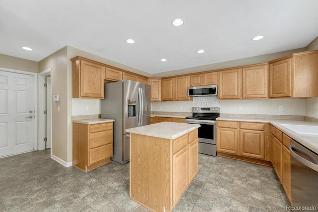 kitchen featuring stainless steel appliances, light countertops, recessed lighting, a kitchen island, and stone finish flooring