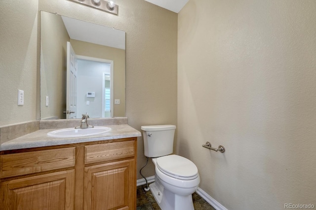 half bath with toilet, vanity, and baseboards