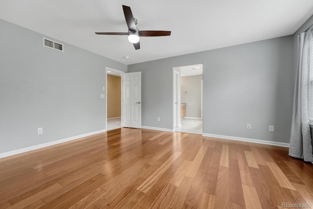 unfurnished bedroom with light wood-style floors, baseboards, a ceiling fan, and ensuite bath