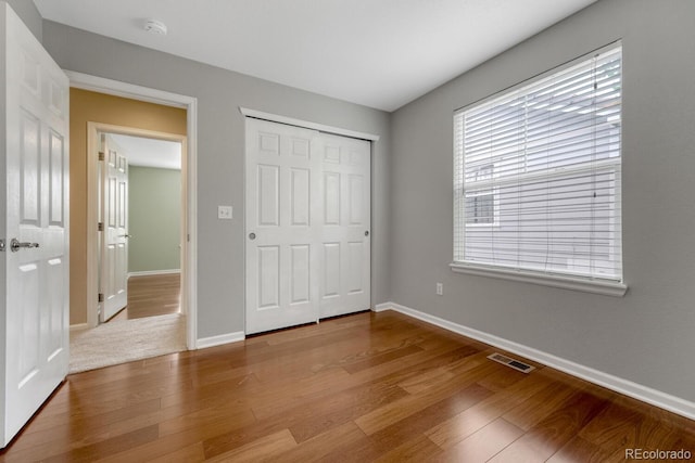 unfurnished bedroom with baseboards, wood finished floors, and a closet