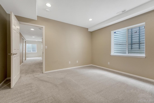 empty room featuring recessed lighting, light carpet, and baseboards